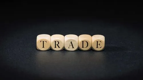 Wooden dice spelling TRADE on a black background