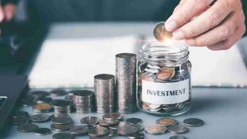 A person places a coin into a glass jar while scattered coins lie outside