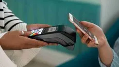 A consumer using a mobile phone for payment with the merchant confirming the transaction through a detector
